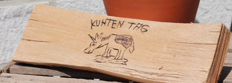 Kuhten Tag - Ein Einhorn, das aussieht wie eine Kuh eingebrannt in ein Stück Holz.